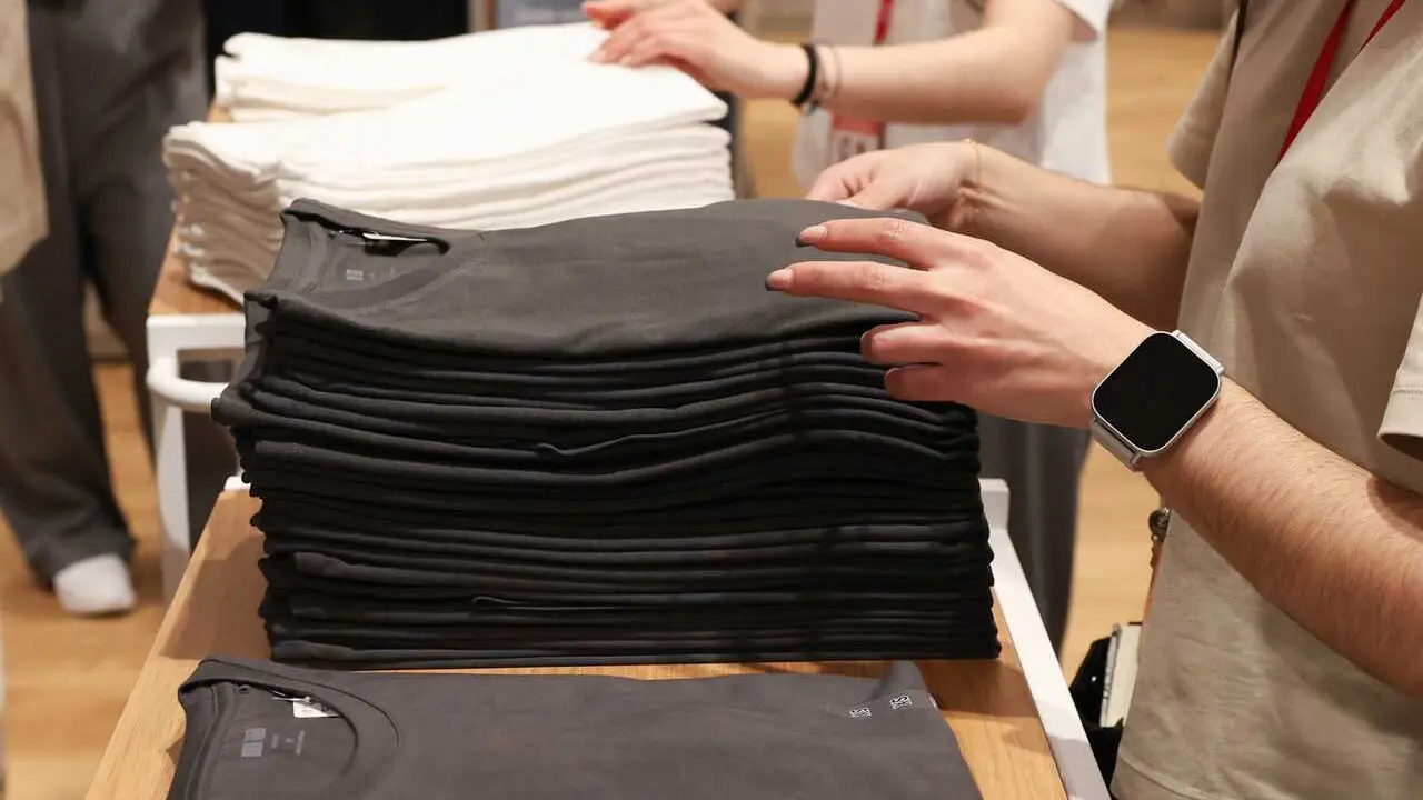 Archivo - Varios dependientes colocan ropa en una tienda de moda 