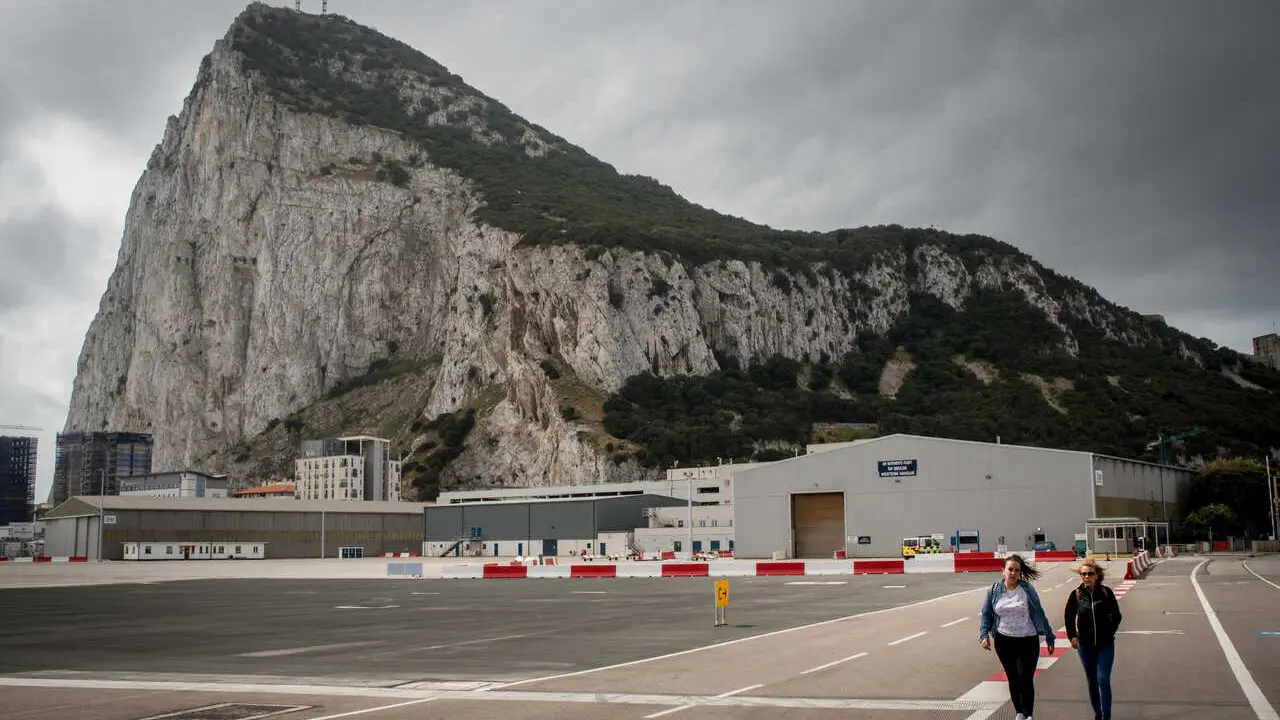 Pedestrians crossing  the asphalt at Gibraltar international airport  (British overseas territory)  near the border with Spain.