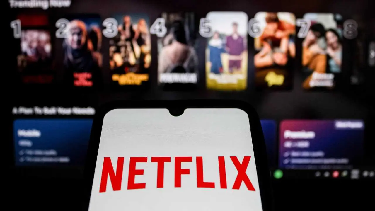 In this photo illustration, the Netflix Logo displayed on a smartphone screen with Netflix website in the background.