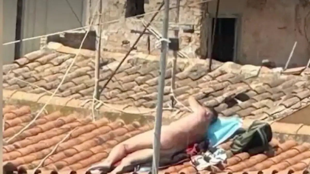 Persona tomando el sol desnuda en un tejado.
