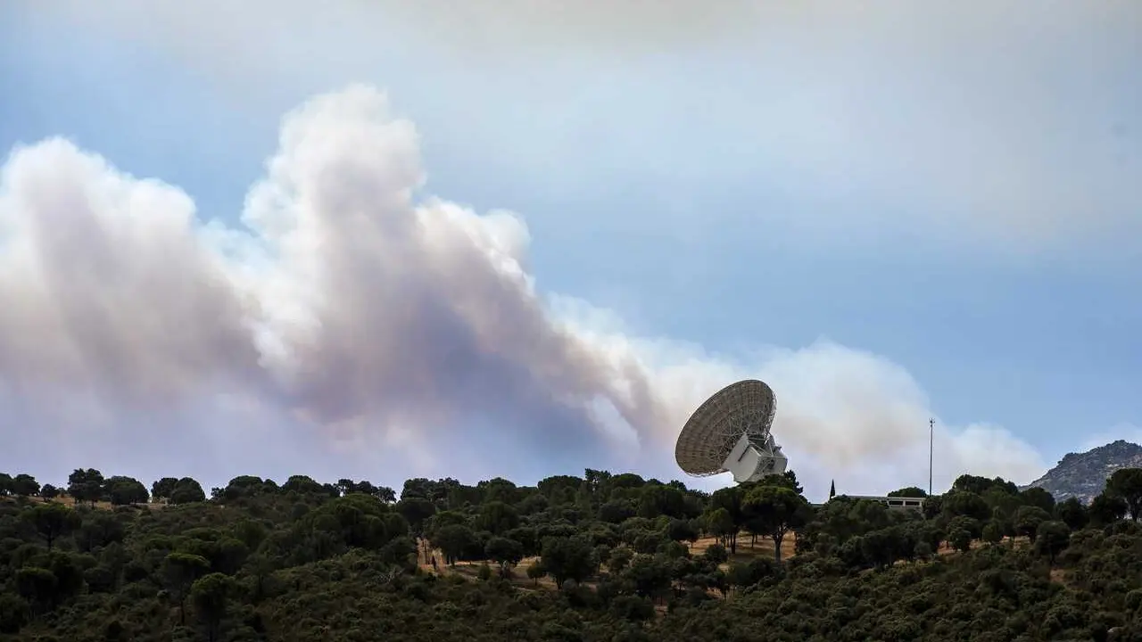 El humo de un fuego cercano sobrevuela una antena de la NASA, a 24 de julio de 2026, en Robledo de Chavela, Madrid (Espa&ntilde;a). Los incendios que afectan a la Comunidad de Madrid siguen avanzando sin control y se han unido en un solo foco, mientras que en &Aacute;v