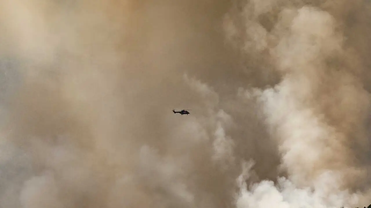 Helic&oacute;ptero vuela entre humo del fuego forestal, a 25 de julio de 2026, en Navaluenga, &Aacute;vila, Castilla y Le&oacute;n (Espa&ntilde;a). El incendio forestal de Burgohondo (&Aacute;vila), que afronta este s&aacute;bado su cuarta jornada, ha obligado a ordenar la evacuaci&oacute;n preventiva d