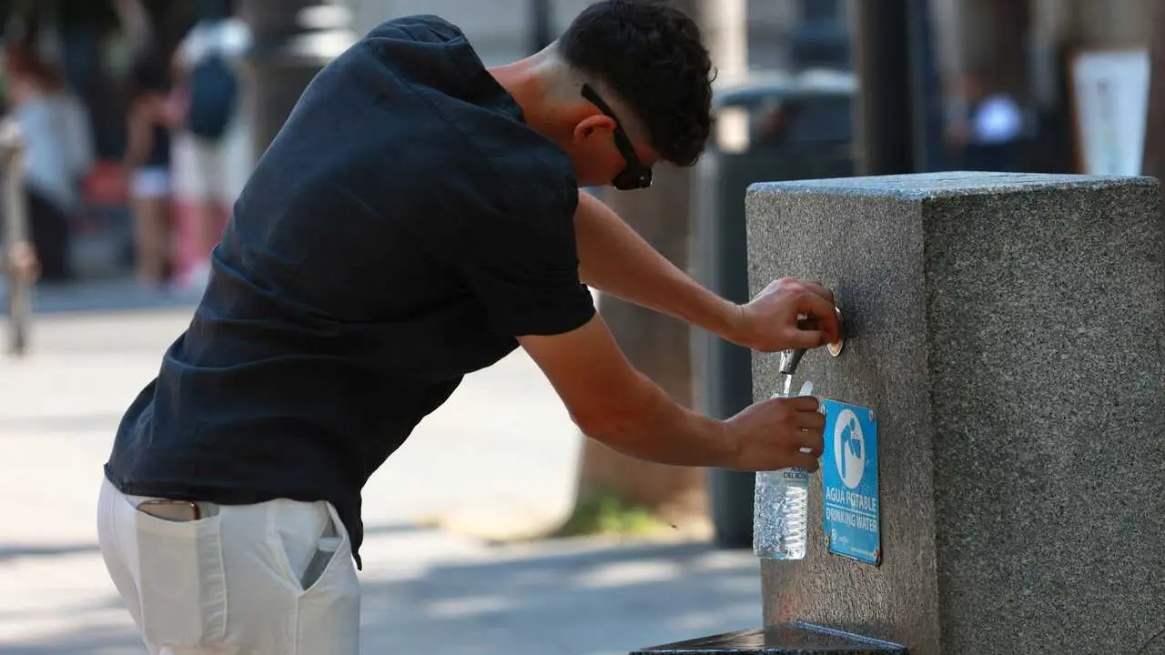 Una persona se refresca en una fuente, en Sevilla (Andaluc&iacute;a, Espa&ntilde;a). 
