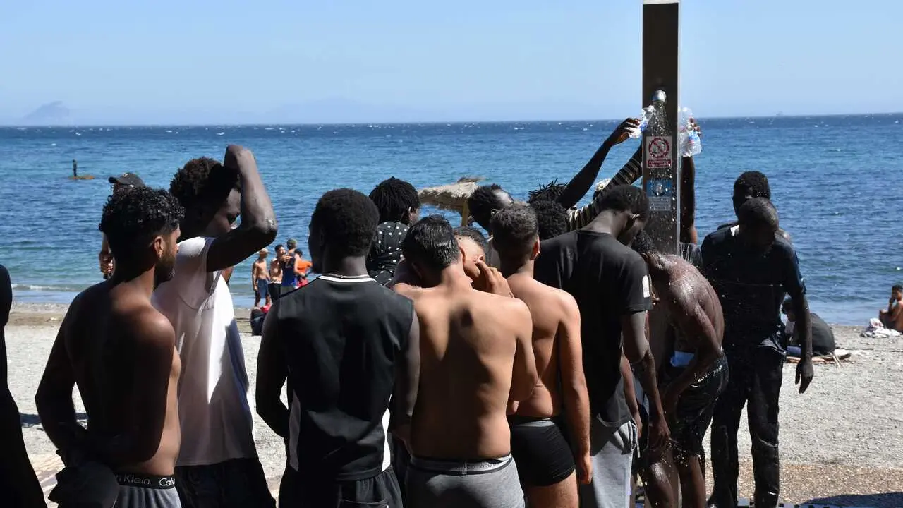 Varias personas se asean en las duchas p&uacute;blicas, en la playa del Trampol&iacute;n, a 5 de agosto de 2026, en Ceuta (Espa&ntilde;a). La Polic&iacute;a Nacional ha comenzado el proceso de triaje de los migrantes que permanecen en Ceuta, 'unos 2.500' seg&uacute;n informaciones de la De