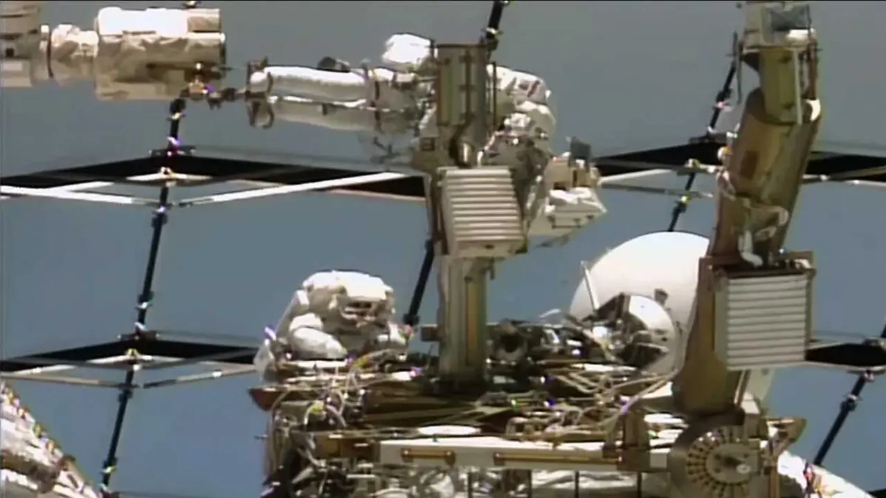 De arriba abajo, los astronautas Anil Menon de la NASA y Sophie Adenot de la ESA (Agencia Espacial Europea) trabajan en una antena de comunicaci&oacute;n espacio-tierra en el exterior de la Estaci&oacute;n Espacial Internacional.