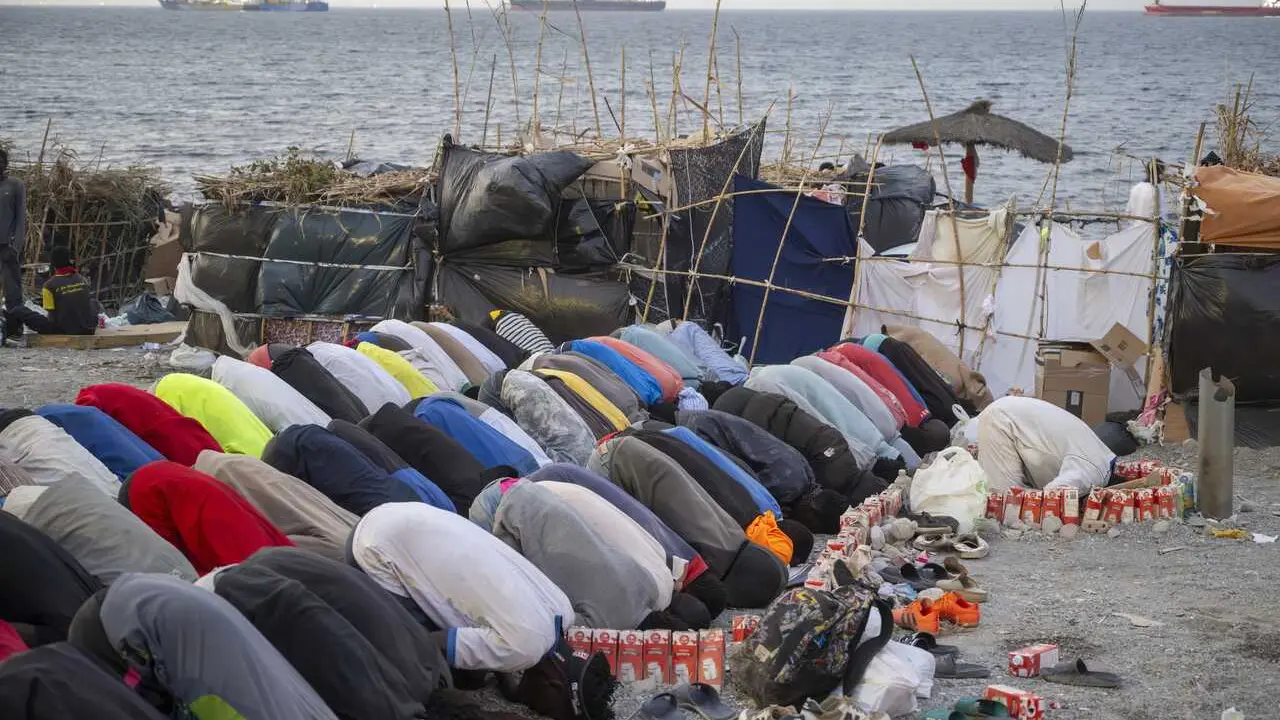 Varios inmigrantes rezan en una playa de Ceuta.