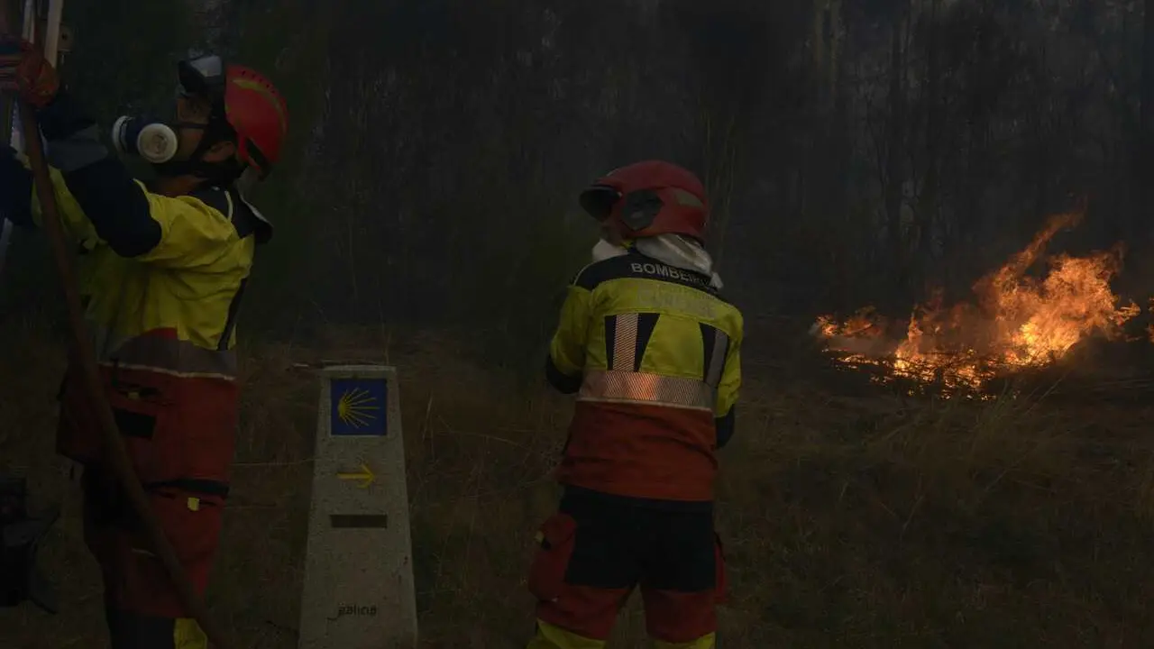 Dos bomberos durante las labores de extinci&oacute;n de un incendio forestal, la carretera nacional 525, a 15 de agosto de 2026, en O Ri&oacute;s, Ourense, Galicia (Espa&ntilde;a).