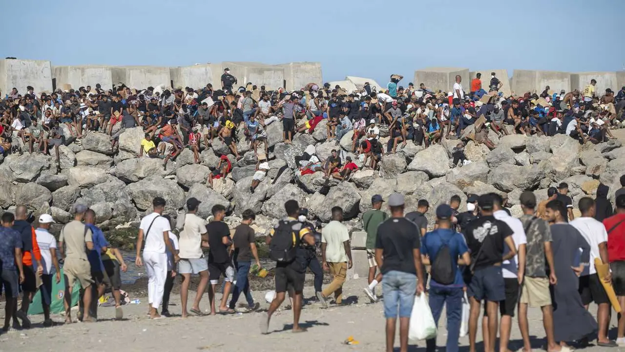 Miembros de la Cruz Roja reparten comida a los inmigrantes en una playa, a 21 de agosto de 2026, en Ceuta (Espa&ntilde;a). 