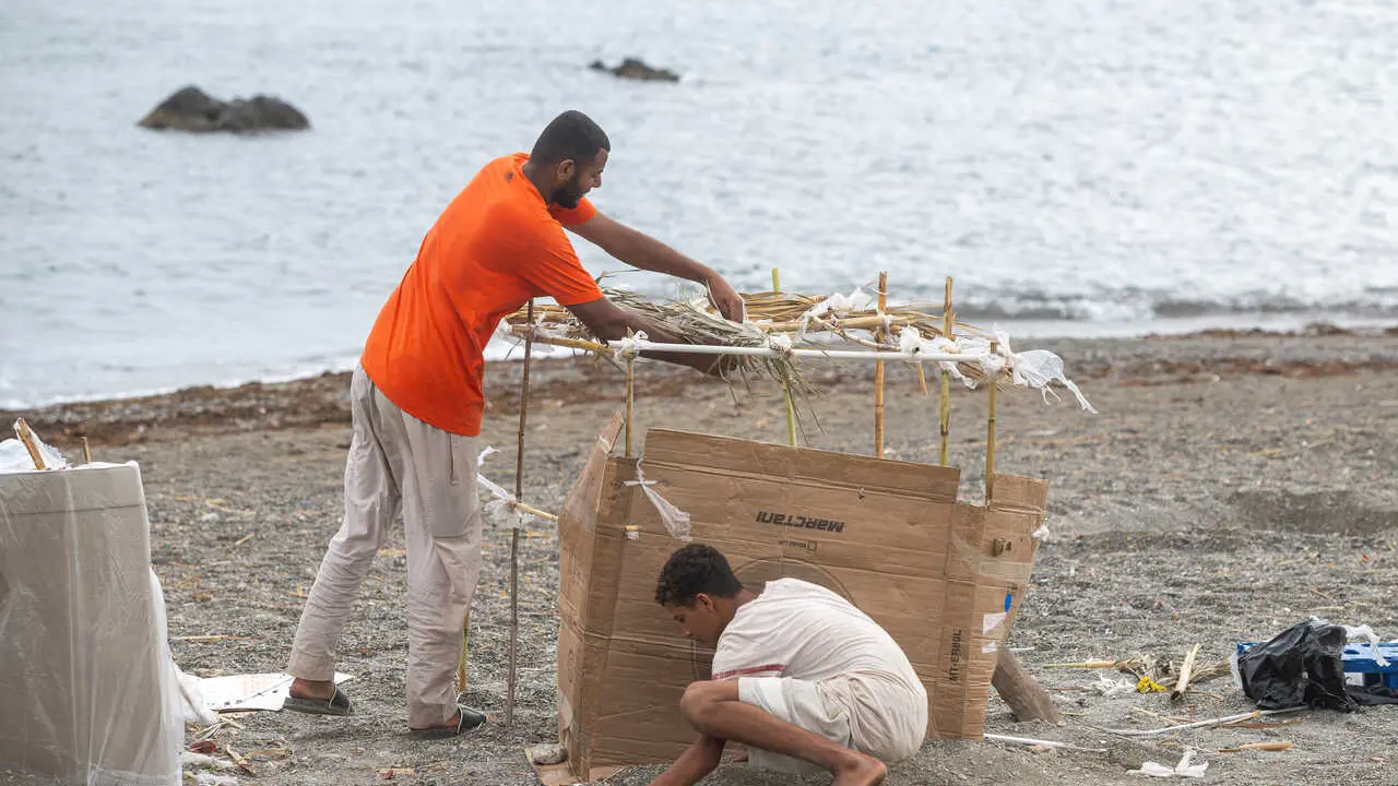 Varios migrantes vuelven a instalarse en la playa El Trampol&iacute;n durante las tareas de limpieza, a 24 de agosto de 2026, en Ceuta (Espa&ntilde;a). 