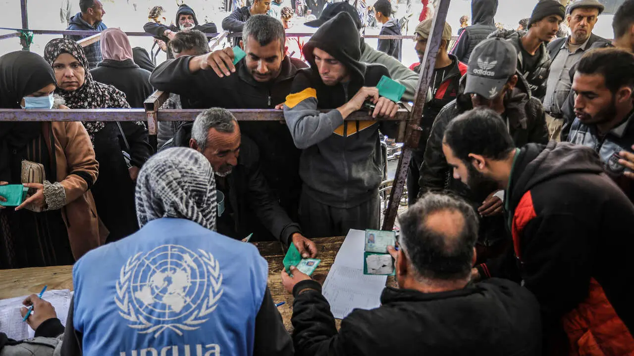 Archivo - Palestinos recibiendo ayuda de personal de UNRWA