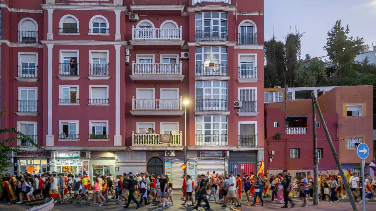 Numerosas personas portan claveles y banderas de Espa&ntilde;a durante una manifestaci&oacute;n ante la Delegaci&oacute;n del Gobierno, a 28 de agosto de 2026, en Ceuta (Espa&ntilde;a). 
