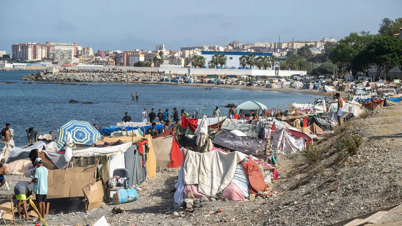 Decenas de migrantes asentados de nuevo en la playa del Trampol&iacute;n, a 31 de agosto de 2026, en Ceuta (Espa&ntilde;a). 