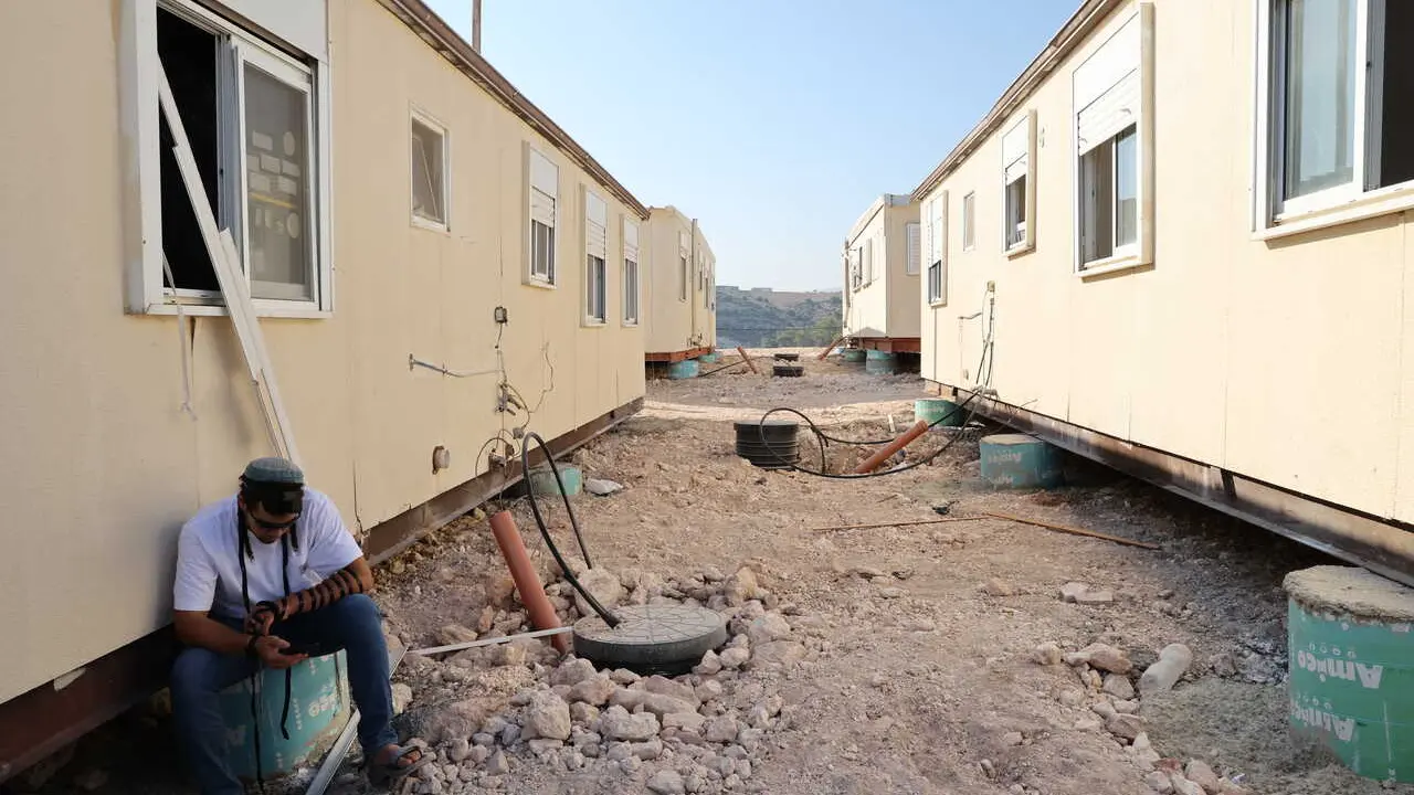 Un colono jud&iacute;o est&aacute; sentado junto a unas casas prefabricadas en el asentamiento de Ganim, en Cisjordania, el 13 de agosto de 2026.
