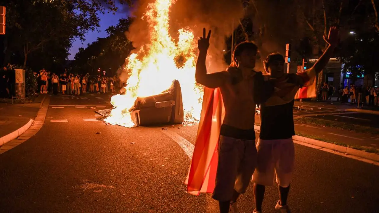 Activistas posan ante un contenedor en llamas en Barcelona durante la Diada de Catalunya